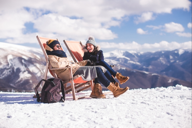 Female couple on chairs on a snow capped mountain