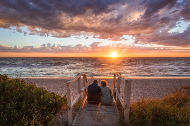 Couple sitting on wooden steps looking out to the coast in australia