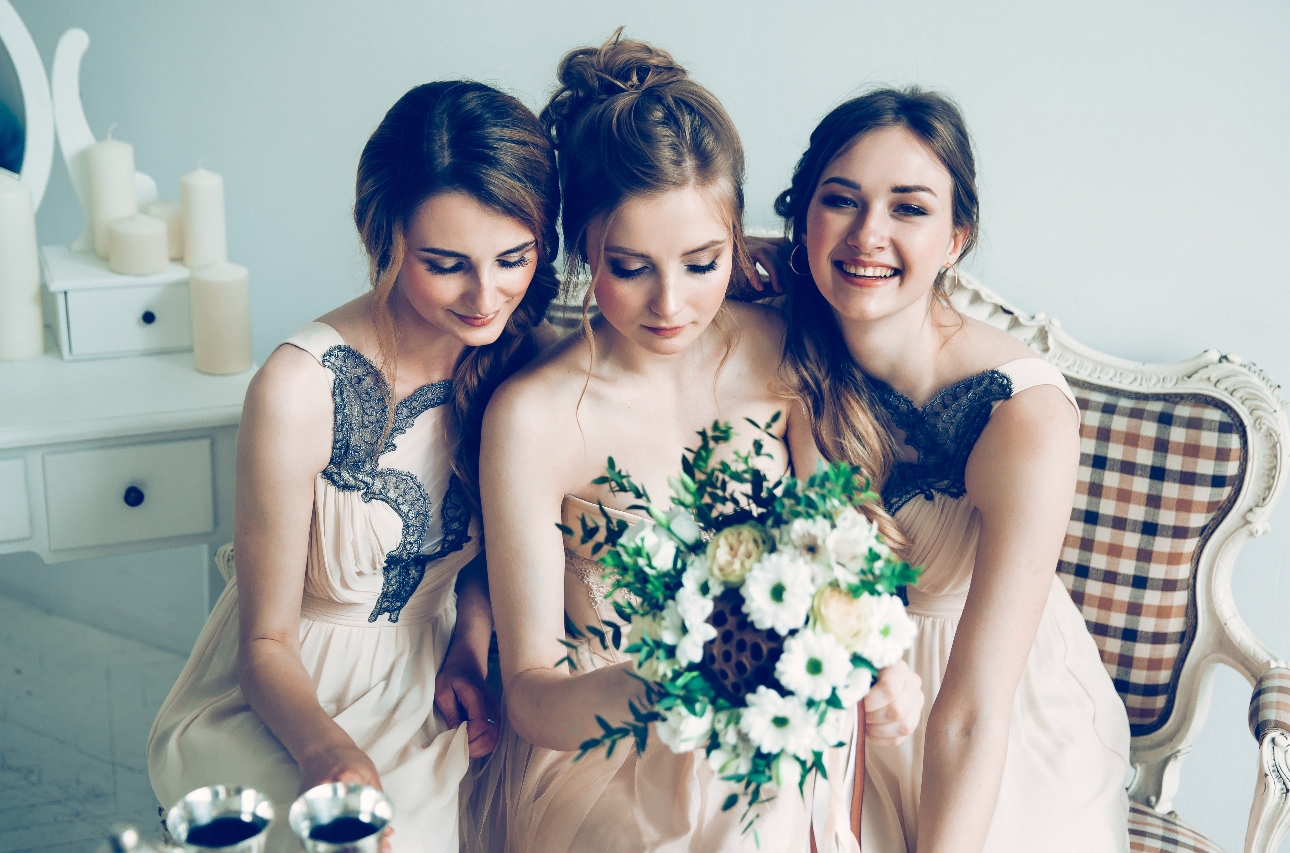 Brides and bridesmaids look at bridal bouquet