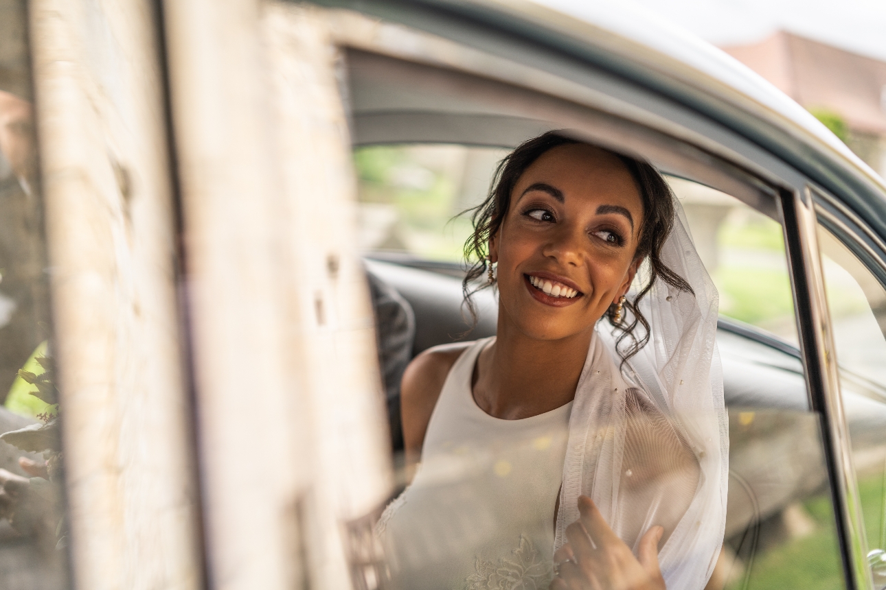 Bride smiles in the back of a Jaguar