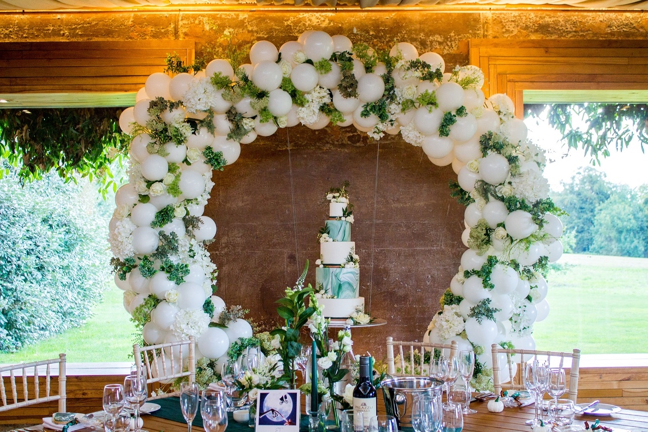 Wedding cake under balloon and flower arch