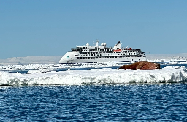 A boat going past a walrus asleep on a piece of ice